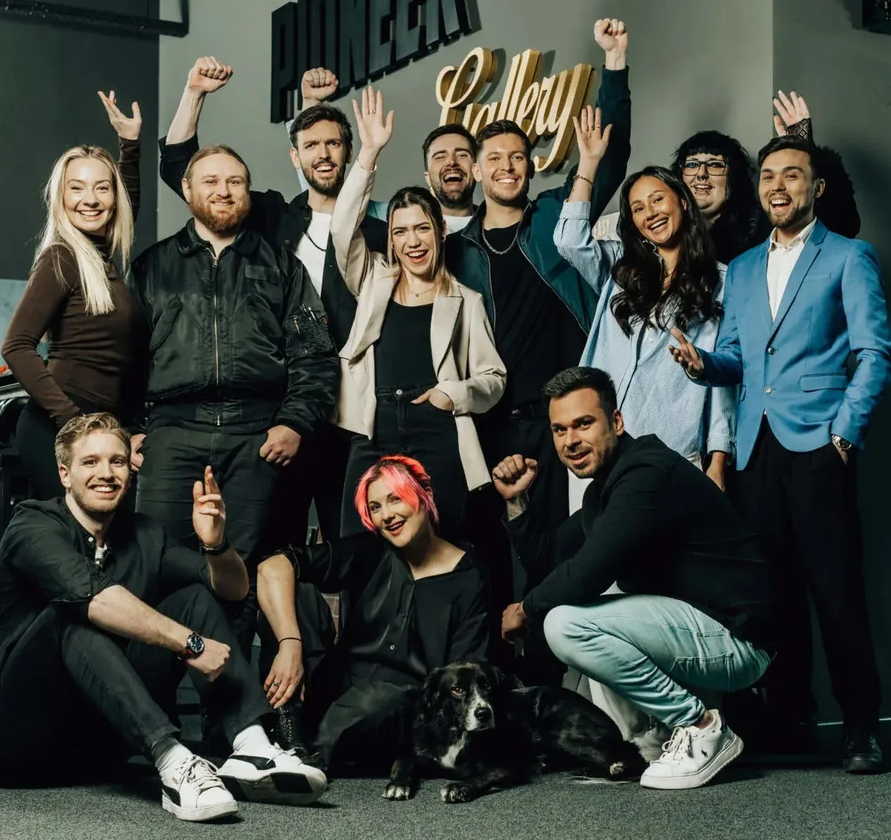 we make marketing Teamfoto mit jubelnden Mitarbeitern und Hund in modernem Büro