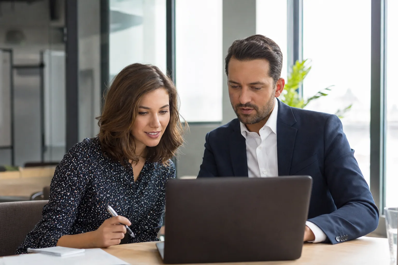 Zwei Geschäftsleute besprechen ein Projekt am Laptop, SEO für B2B von we make marketing